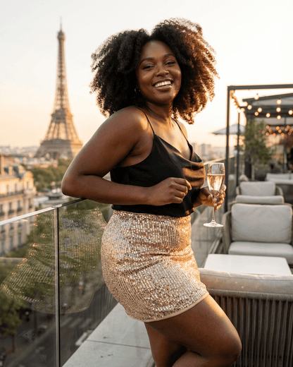 Woman wearing Lumiere Mini Skirt by Slimona, smiling on a rooftop with Eiffel Tower in the background.