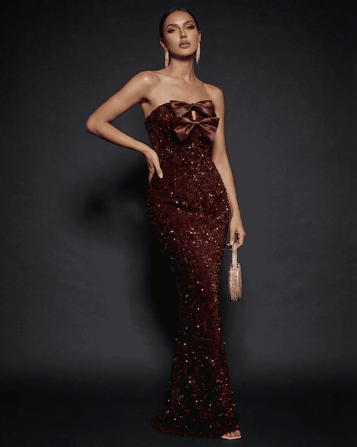 Stunning model showcasing the Marquise Maxi Dress by Slimona, a strapless sequin gown with a bold satin bow.