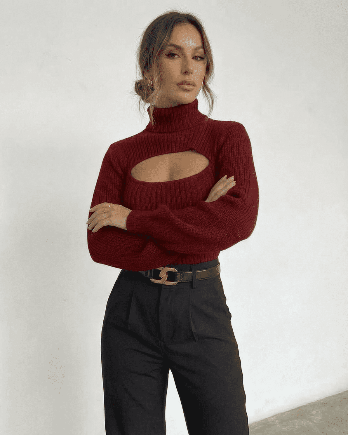 Elegant woman wearing a Slimona Merlot Sweater with a mock neck and cut out detail, paired with stylish black trousers.