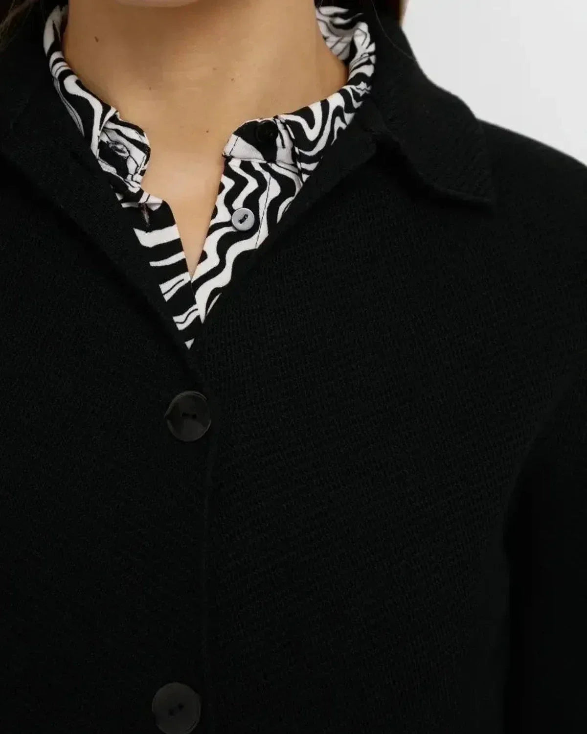 Close-up of Slimona Noir Jacket showcasing button closure and dropped shoulder design, layered with a patterned blouse.