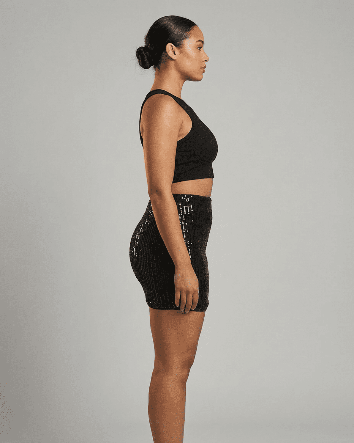 Noiré Mini Skirt by Slimona on a model showcasing the sleek sequin high waist bodycon design from the side.