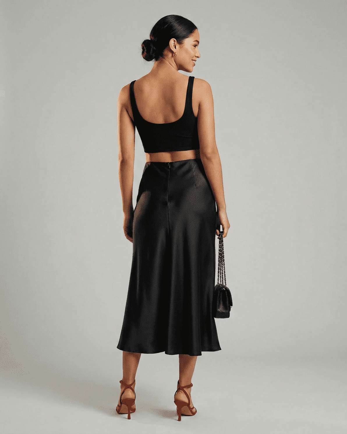 Model showcasing the Noirelle Midi Skirt by Slimona, featuring a sleek satin mermaid design in classic black.