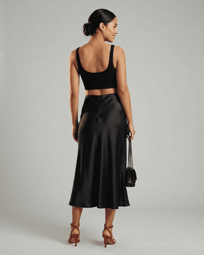 Model showcasing the Noirelle Midi Skirt by Slimona, featuring a sleek satin mermaid design in classic black.