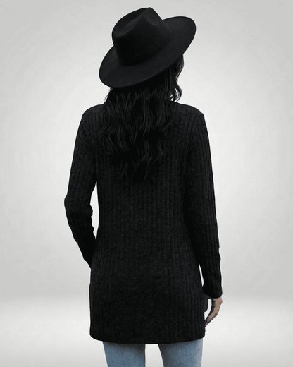 Back view of a woman in a longline Nyx Cardigan by Slimona, featuring a textured knit and a black hat.