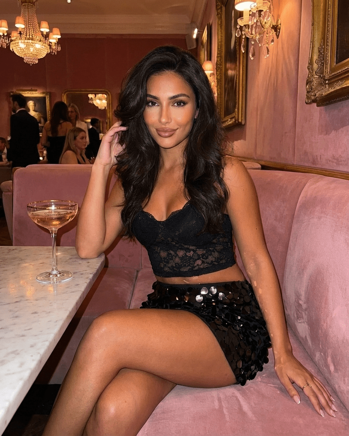 Obsidian Mini Skirt by Slimona worn by a model in a stylish setting with a drink, showcasing black sequin hem bodycon design.