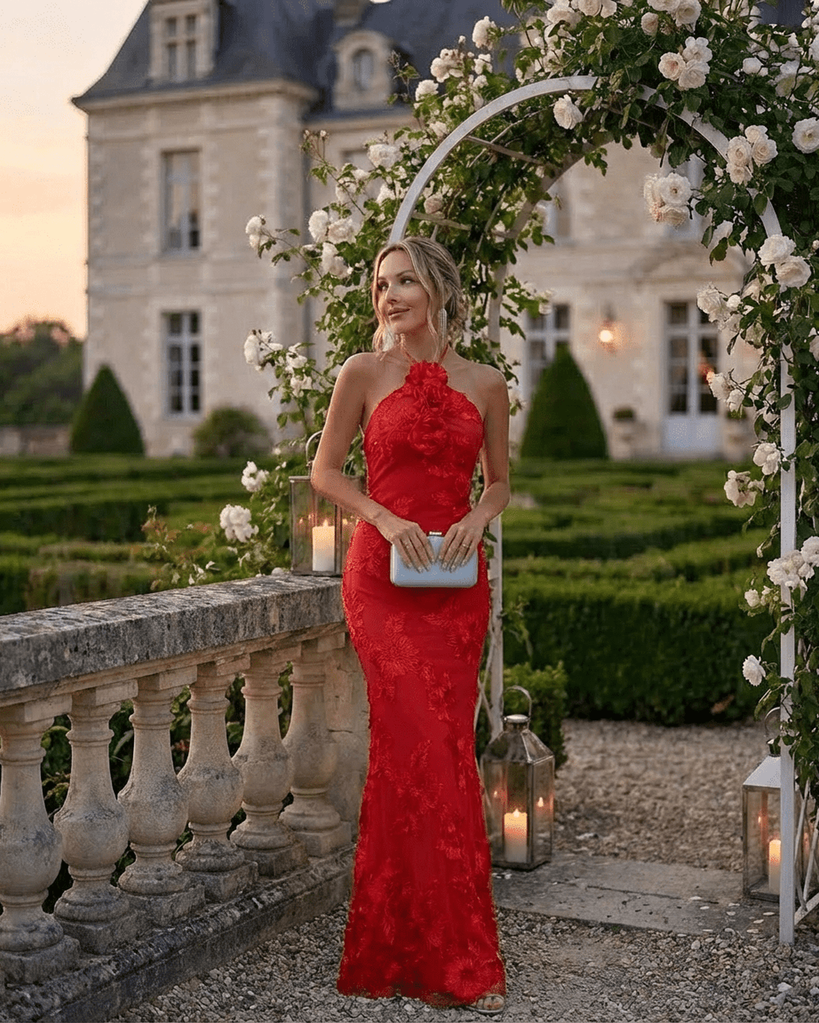 Rosalia Maxi Dress by Slimona, elegant halter neck design in bold red with 3D floral detail in a picturesque garden setting.