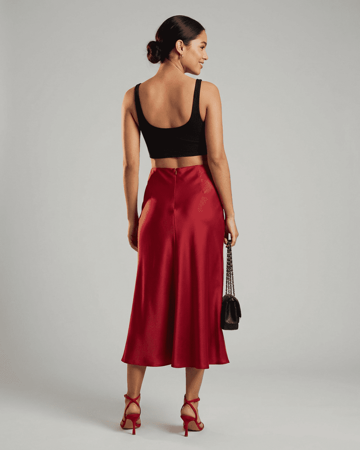 Back view of a model wearing the Rosalia Midi Skirt by Slimona, showcasing its elegant satin mermaid design in rich red.