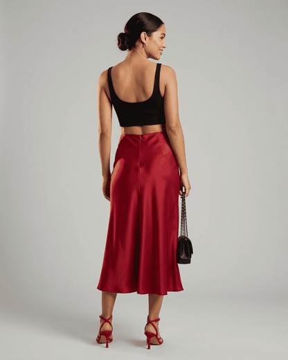 Back view of a model wearing the Rosalia Midi Skirt by Slimona, showcasing its elegant satin mermaid design in rich red.