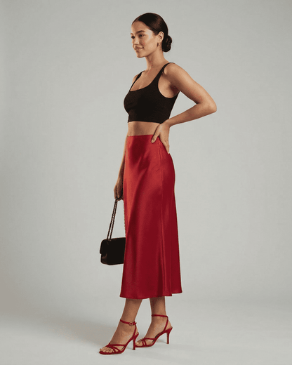 Model showcasing Rosalia Midi Skirt by Slimona, a refined satin mermaid midi skirt in rich red hue.