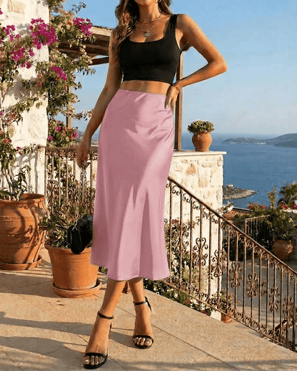 Woman wearing a black crop top and Roselle Midi Skirt by Slimona, posing outdoors with a coastal view.
