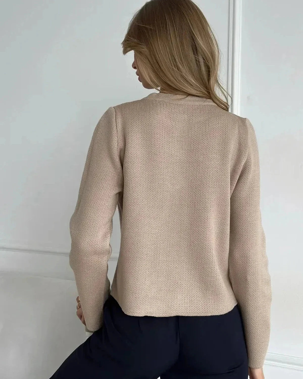 Back view of a woman wearing the Sable Cardigan by Slimona, showcasing its elegant beige cropped design.