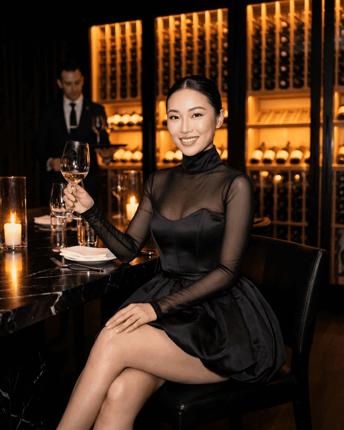 Elegant woman in Selene Mini Dress by Slimona, seated at a restaurant, holding a wine glass, exuding sophistication.