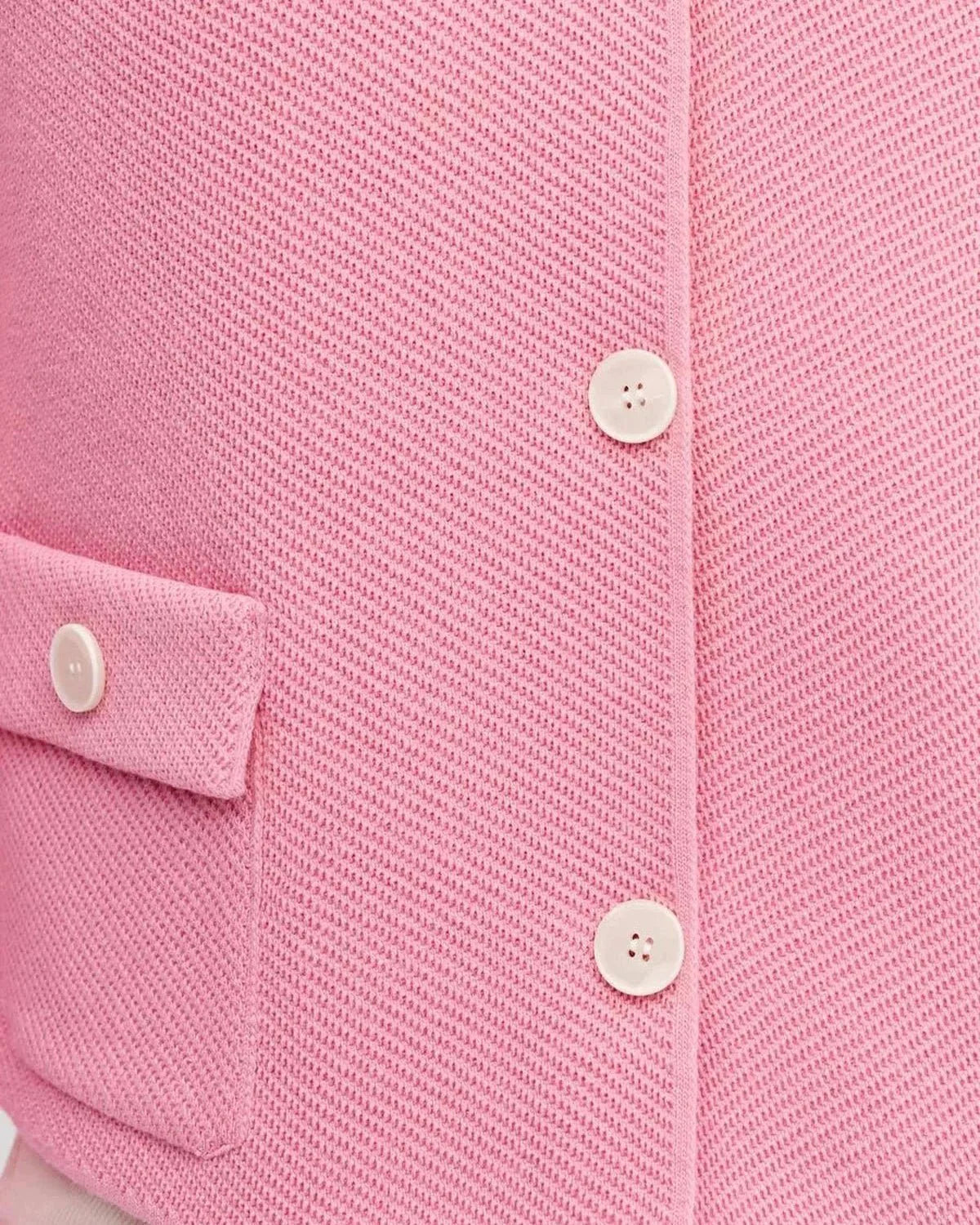 Close-up of the Serena Jacket by Slimona, showcasing its textured pink fabric and button closure.