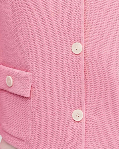 Close-up of the Serena Jacket by Slimona, showcasing its textured pink fabric and button closure.