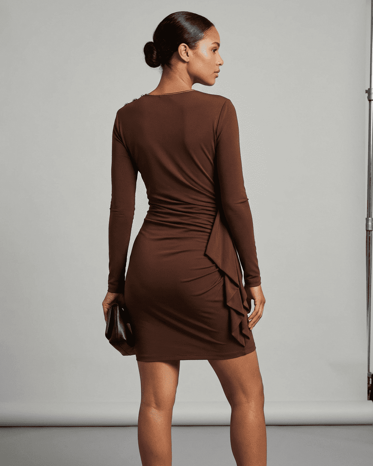 Back view of a model wearing the Sienna Mini Dress by Slimona, showcasing its ruched bodycon design.