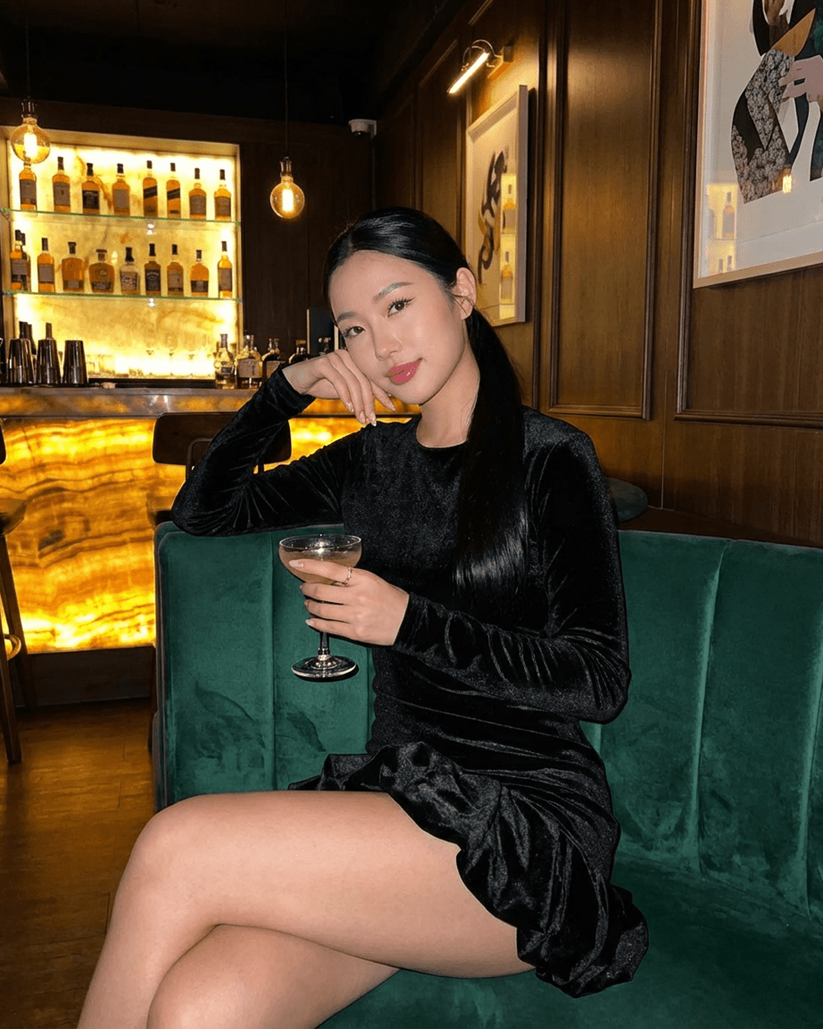 Model wearing Velora Mini dress by Slimona, showcasing the luxe velvet fabric and pleated hem while enjoying a cocktail.