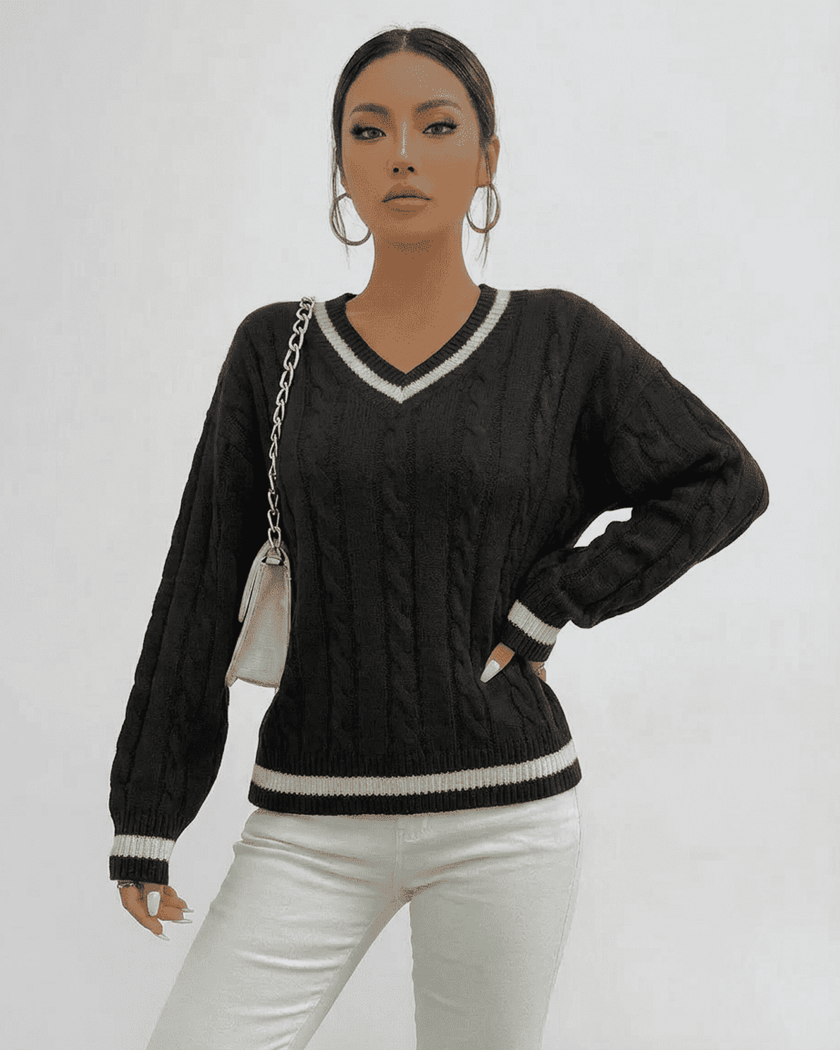 Model wearing a black Verona Sweater with cable knit design and V-neck silhouette, styled with a chic handbag.