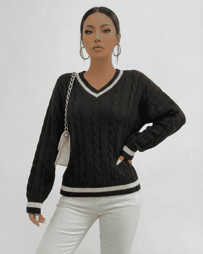 Model wearing a black Verona Sweater with cable knit design and V-neck silhouette, styled with a chic handbag.