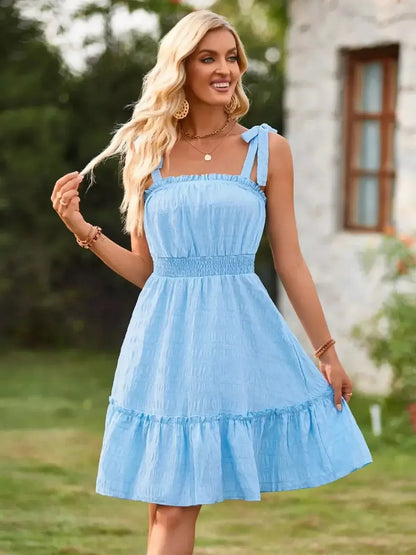 Light blue sundress with tie straps and a flowy skirt, perfect for summer outdoor events.