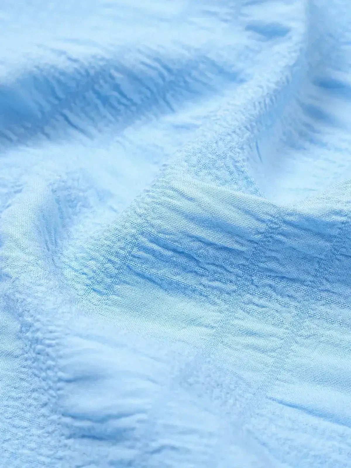 Light blue fabric with a textured, soft finish, ideal for summer dresses and casual wear.