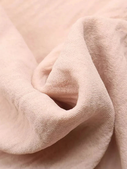 Close-up of soft, textured fabric in light pink, perfect for summer dresses and casual wear.