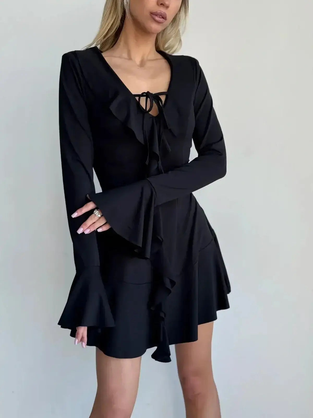 Black long sleeve mini dress with ruffles and tie-front accent, perfect for cocktail parties or formal events.