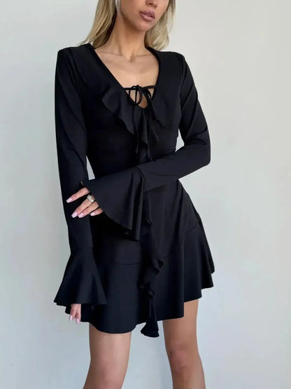 Black long sleeve mini dress with ruffles and tie-front accent, perfect for cocktail parties or formal events.
