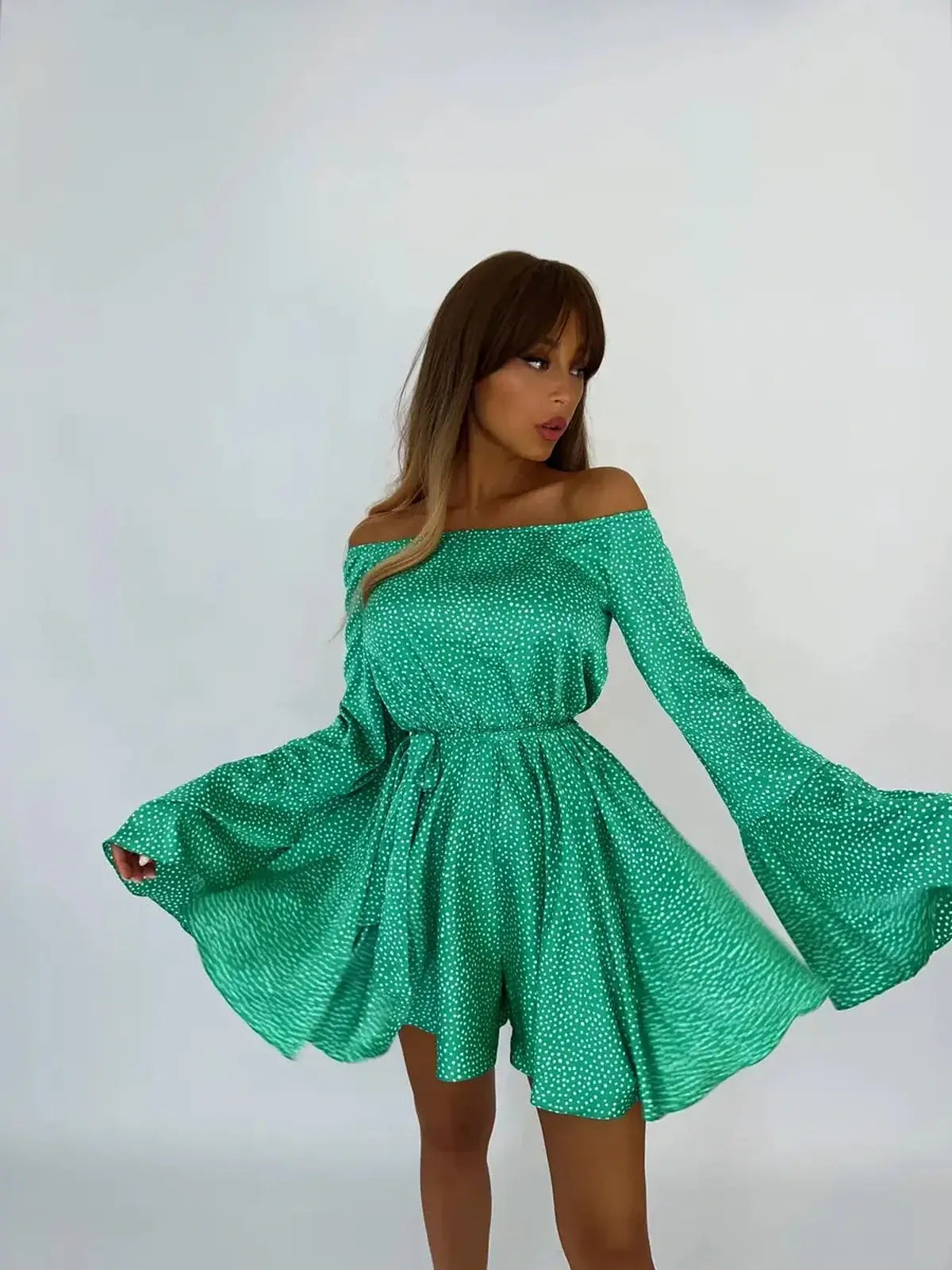 Model wearing the Luna Dot Mini Dress with flared sleeves and a green polka dot print, perfect for summer occasions.