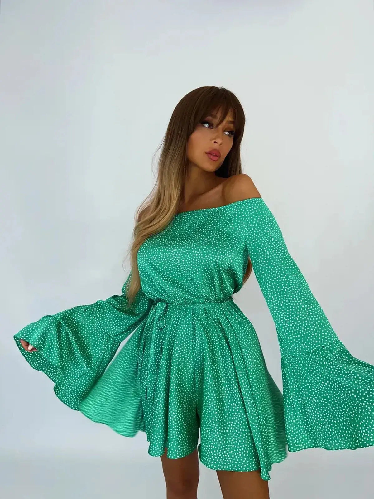 Model wearing a green polka dot mini dress with flared sleeves, perfect for summer outings and special occasions.