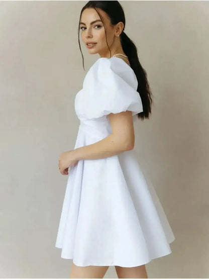 Luna Pearl Mini Dress in white, featuring flirty puff sleeves and a flared skirt, perfect for summer and wedding guest attire.