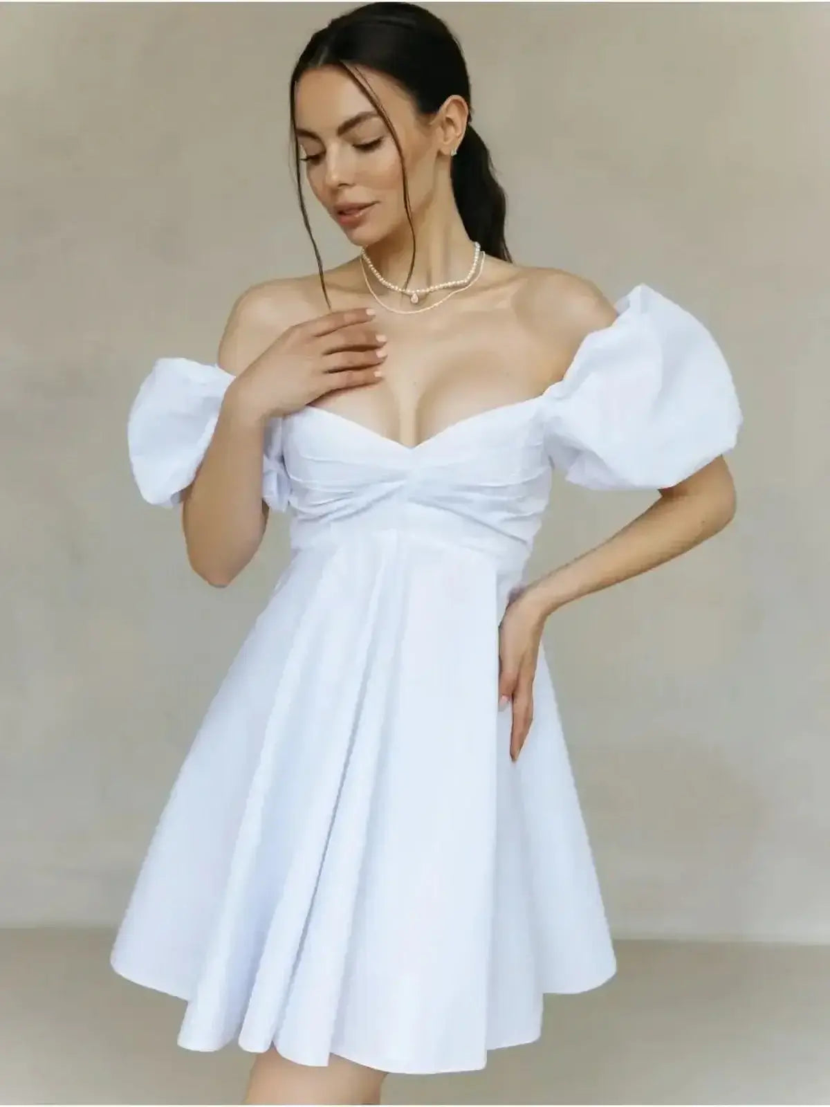 Model wearing the Luna Pearl Mini Dress, a white summer mini dress with puff sleeves and a sweetheart neckline.