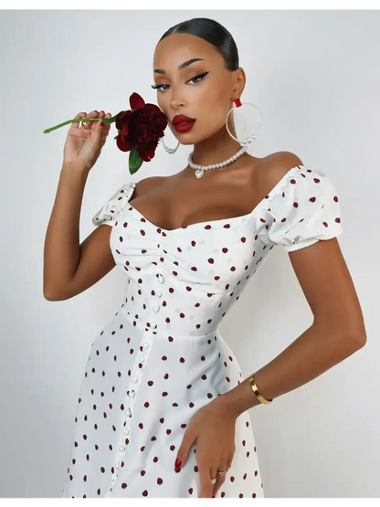 Woman in a white polka dot mini dress with puff sleeves holding a flower, showcasing a chic summer style.