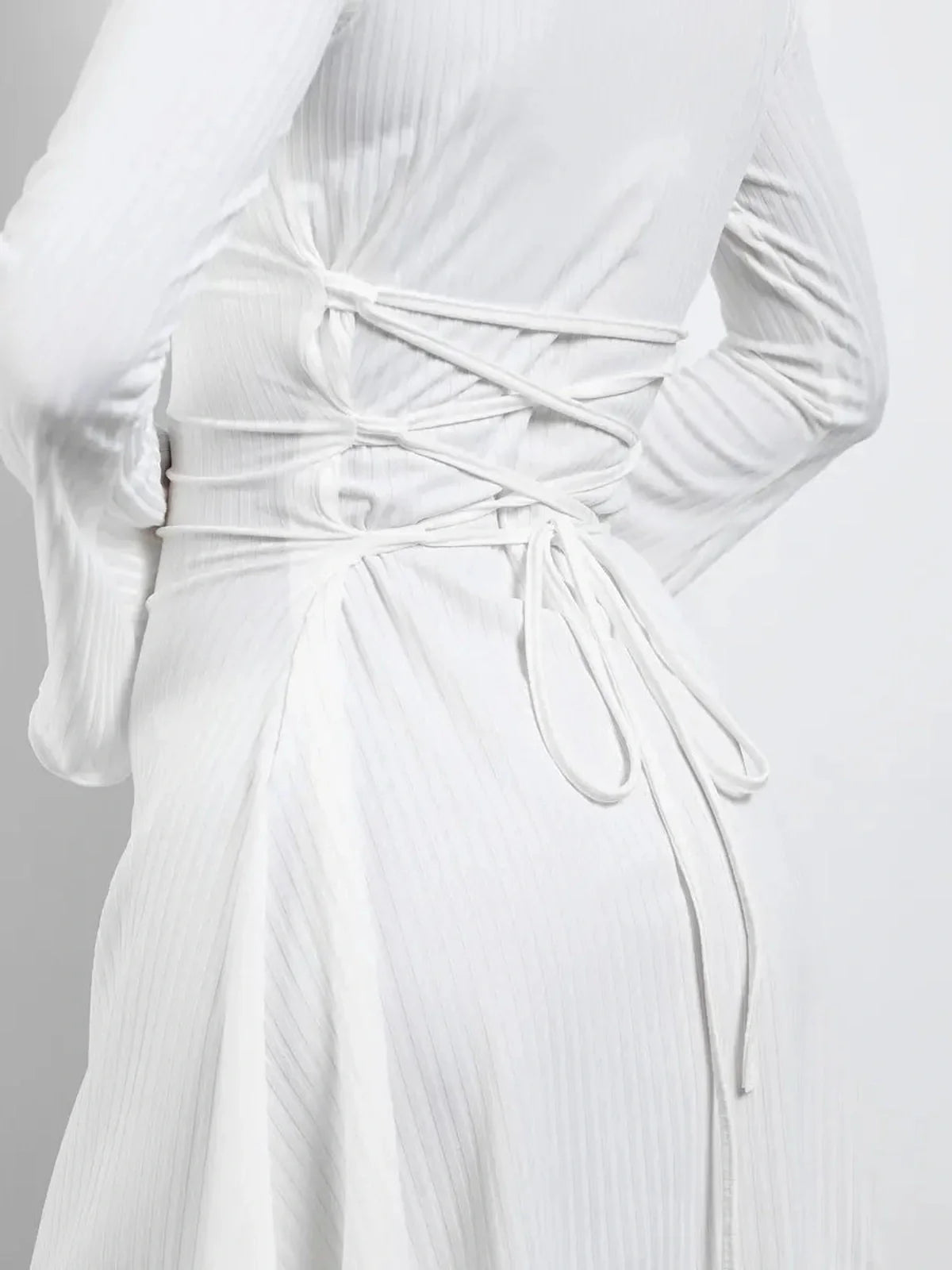 Back view of a white Luxe Lace-Up mini dress showcasing adjustable lace-up detail and flared sleeves.