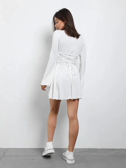Back view of a woman in a white lace-up mini dress, perfect for summer and wedding guest occasions.