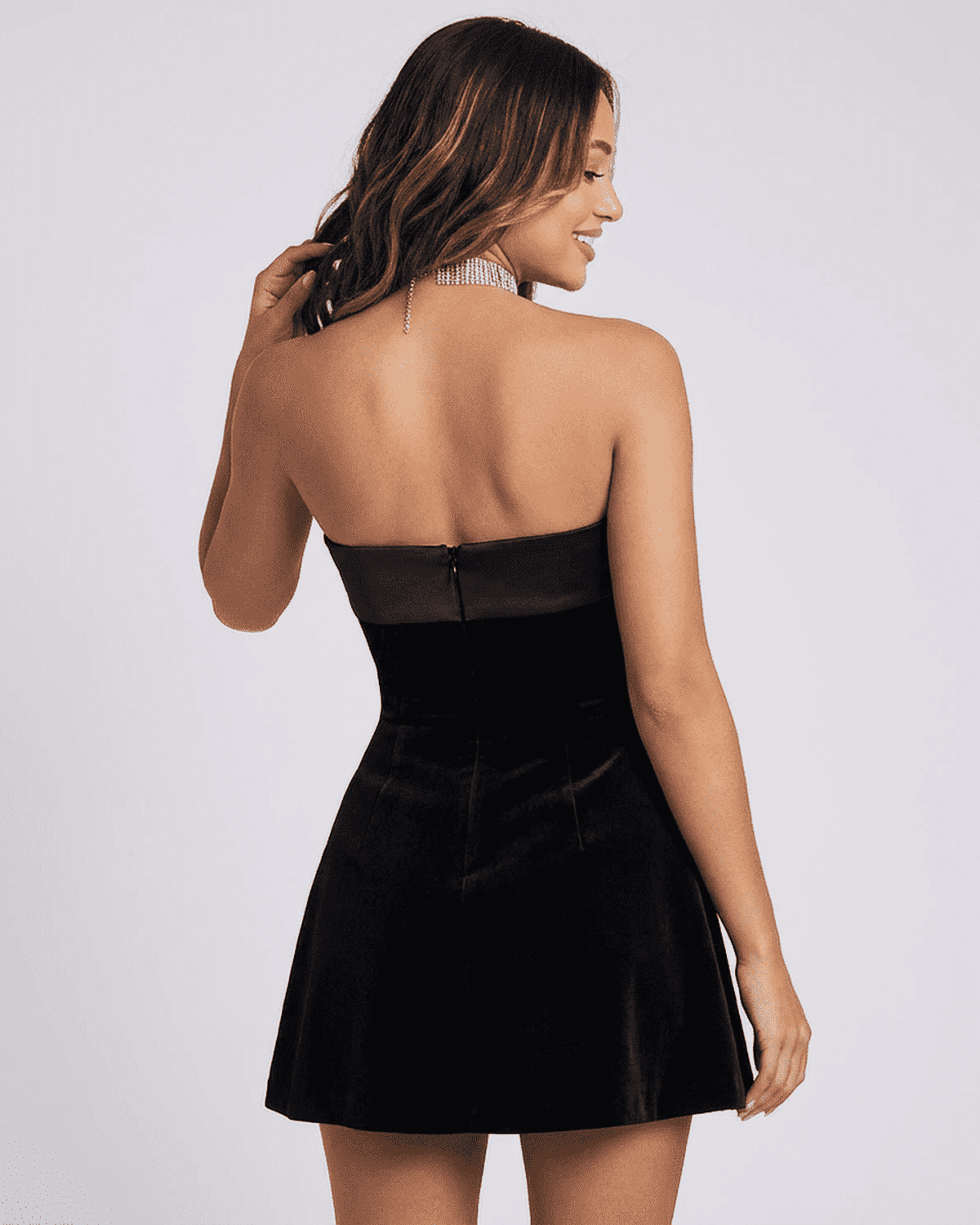 Back view of a woman wearing a Slimona Luxe Mini Dress made from elegant velvet fabric.