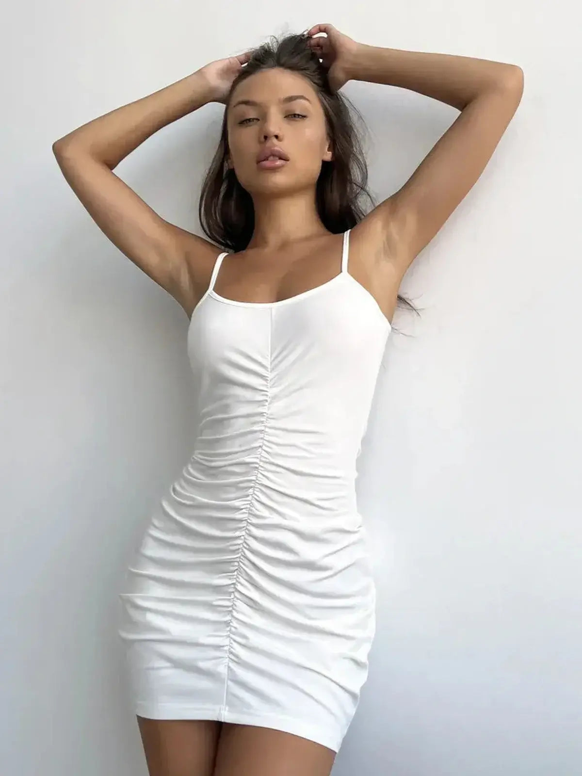Model showcasing a white Luxe Sculpt Mini dress with ruched detail and adjustable spaghetti straps.