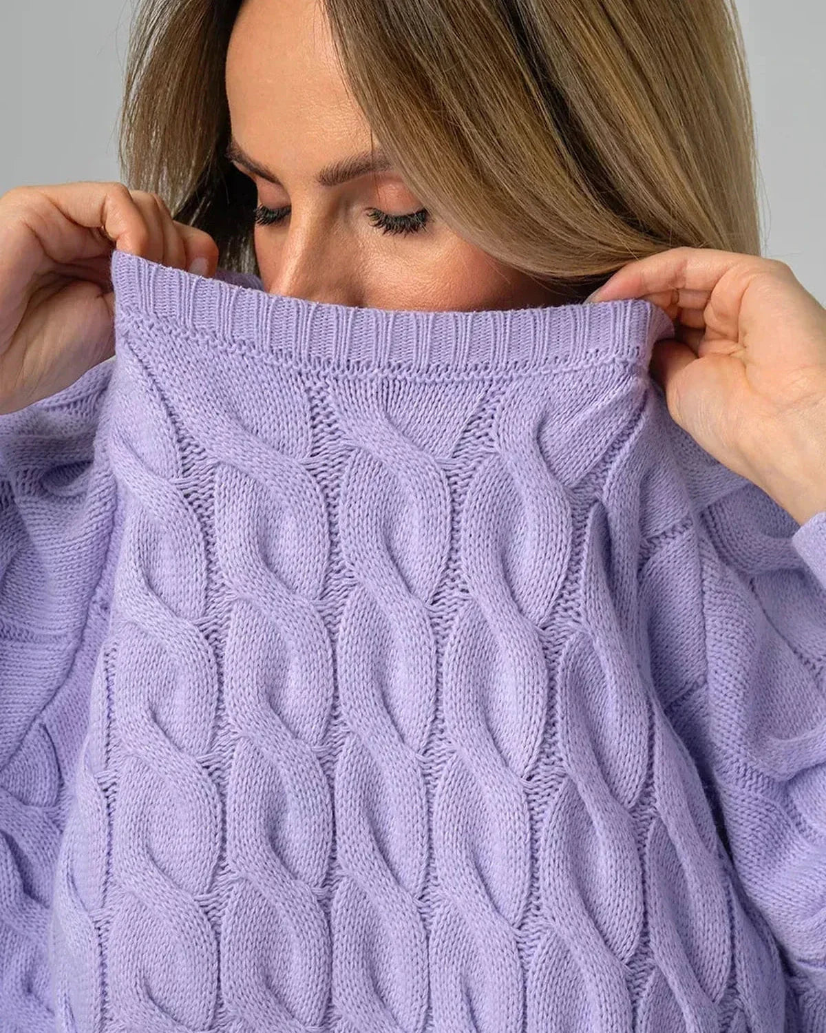 Model wearing the Lyra Sweater by Slimona, showcasing its oversized lavender knit and modern cable design.
