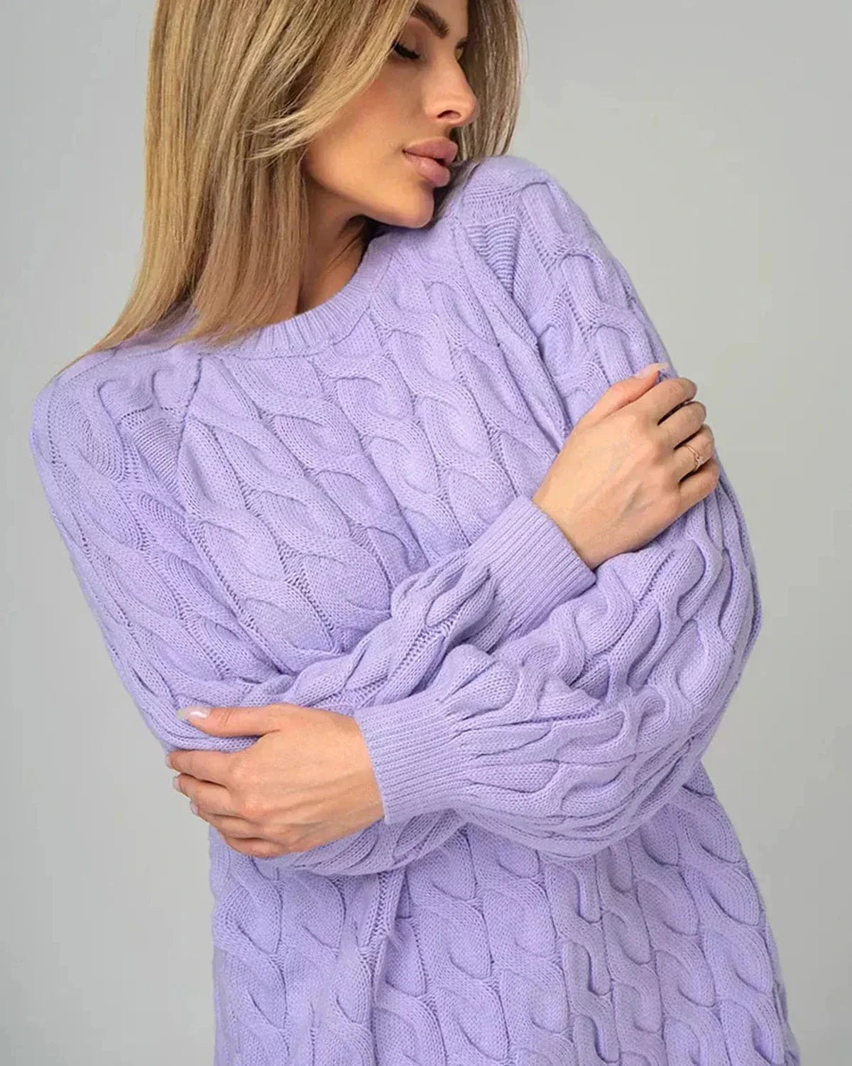 Wearing the Lyra Sweater by Slimona, an oversized lavender knit with modern cable design.