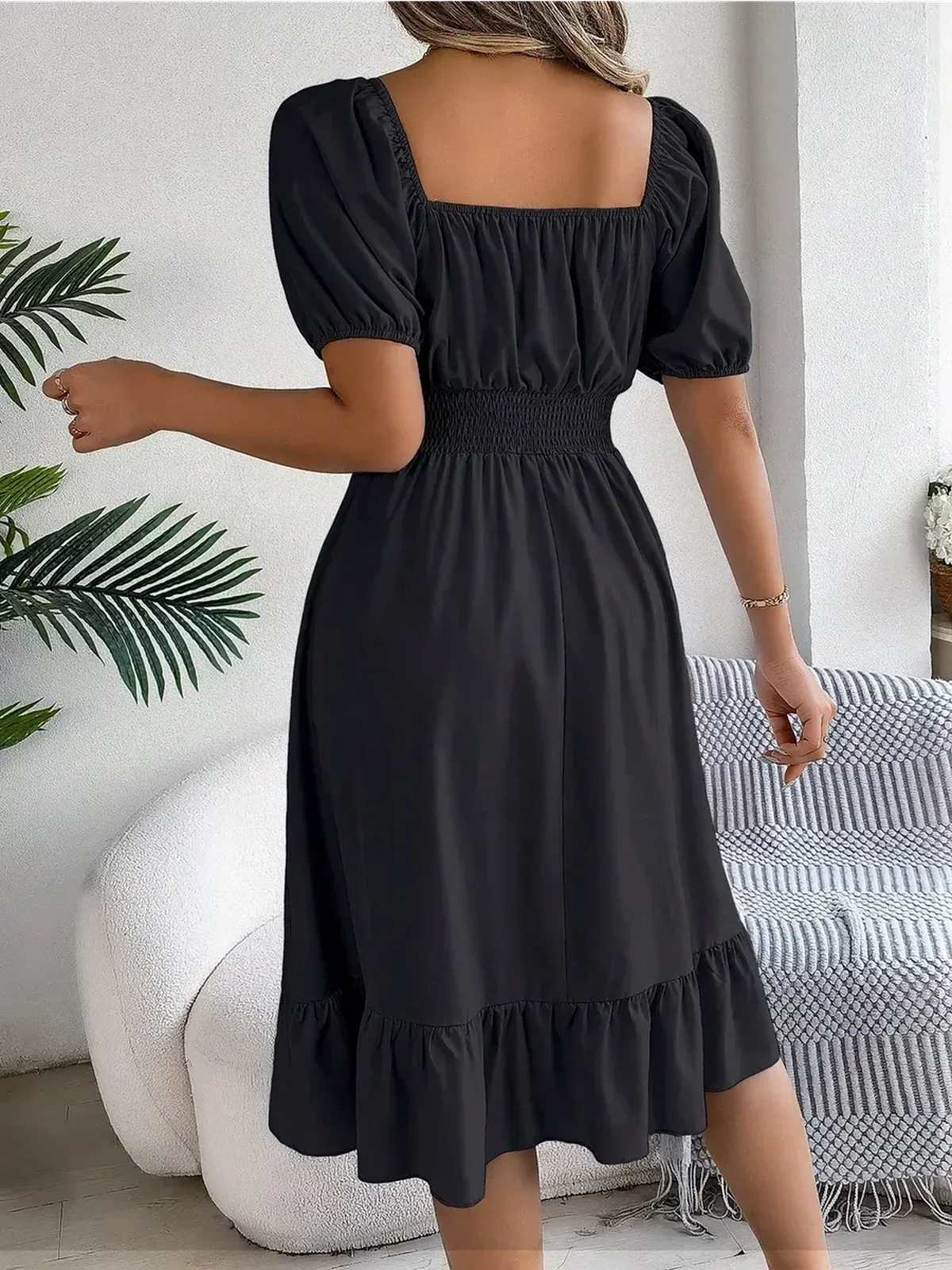Back view of a stylish black mini dress with puff sleeves and a ruffled hem, perfect for summer occasions.