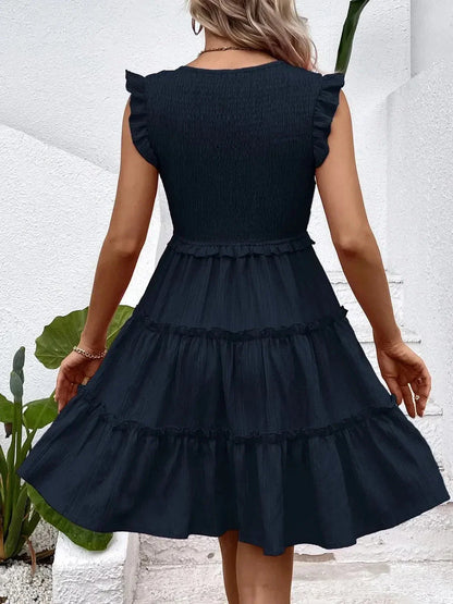 Back view of a model wearing a black frill mini dress with ruffle sleeves and a tiered skirt, perfect for summer occasions.