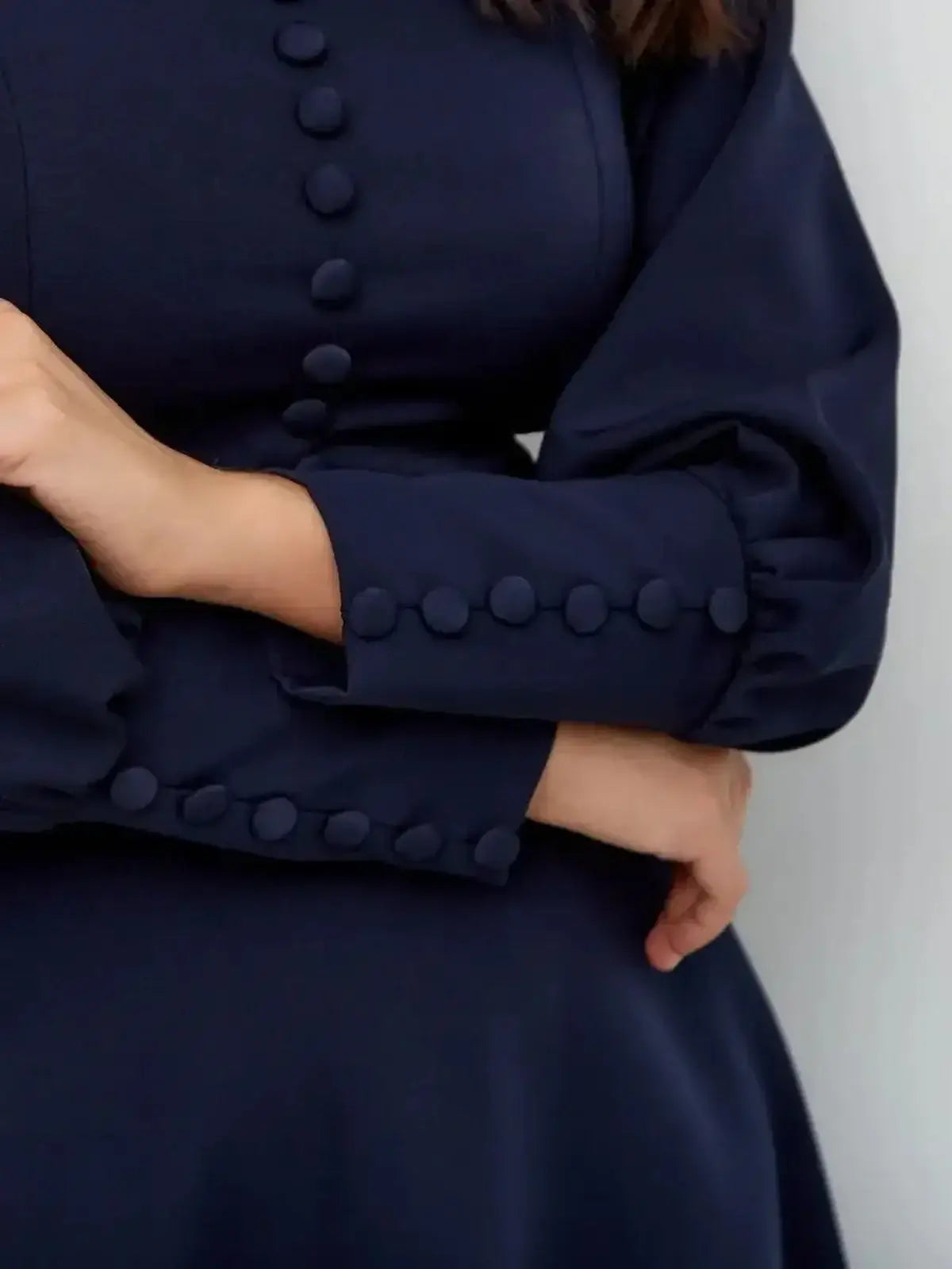 Close-up of the Midnight Grace Mini Dress with navy fabric, square neckline, and sculptural long sleeves with buttons.
