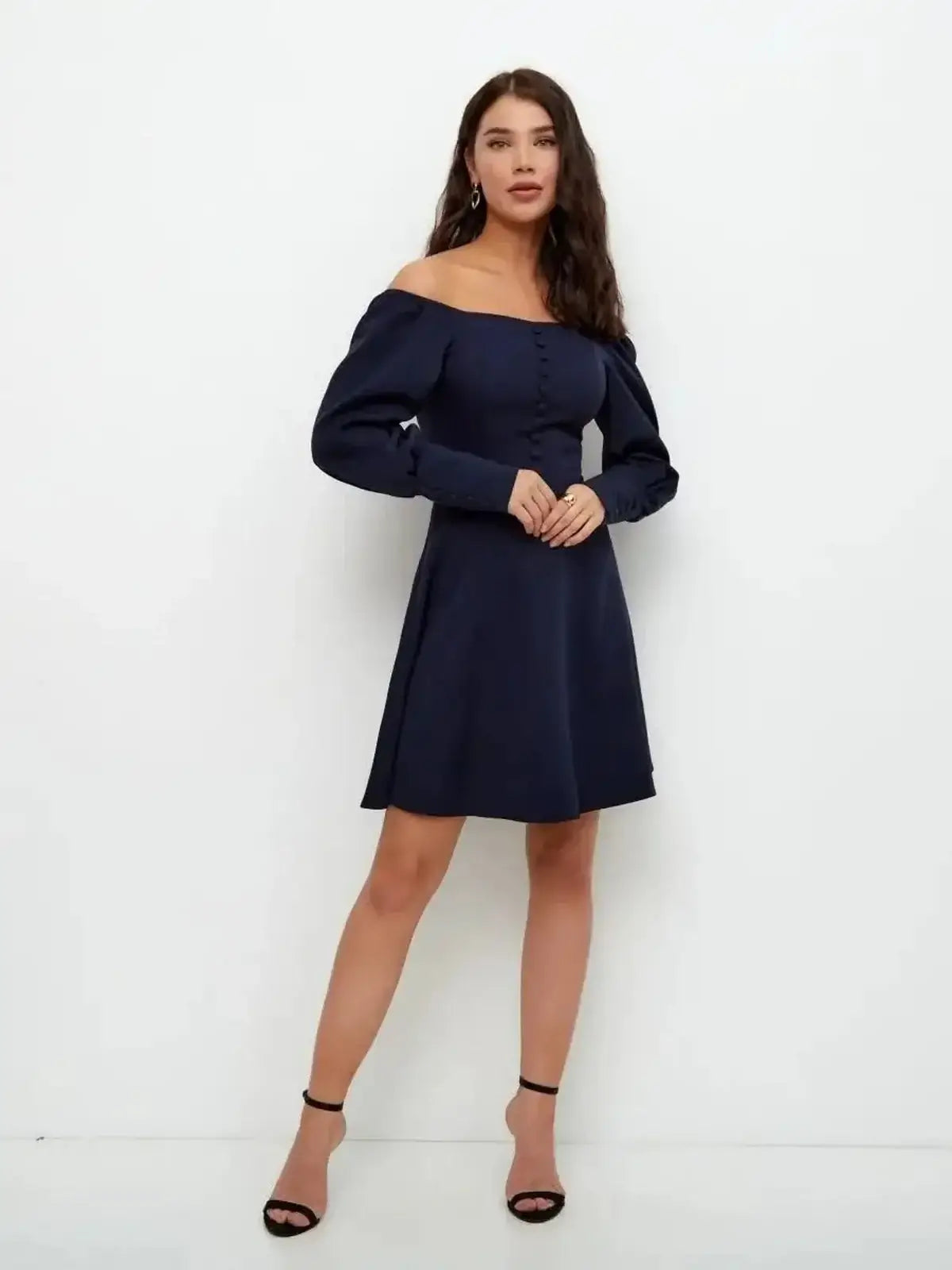 Model wearing a navy blue Midnight Grace Mini Dress featuring an off-shoulder neckline and long sculptural sleeves.