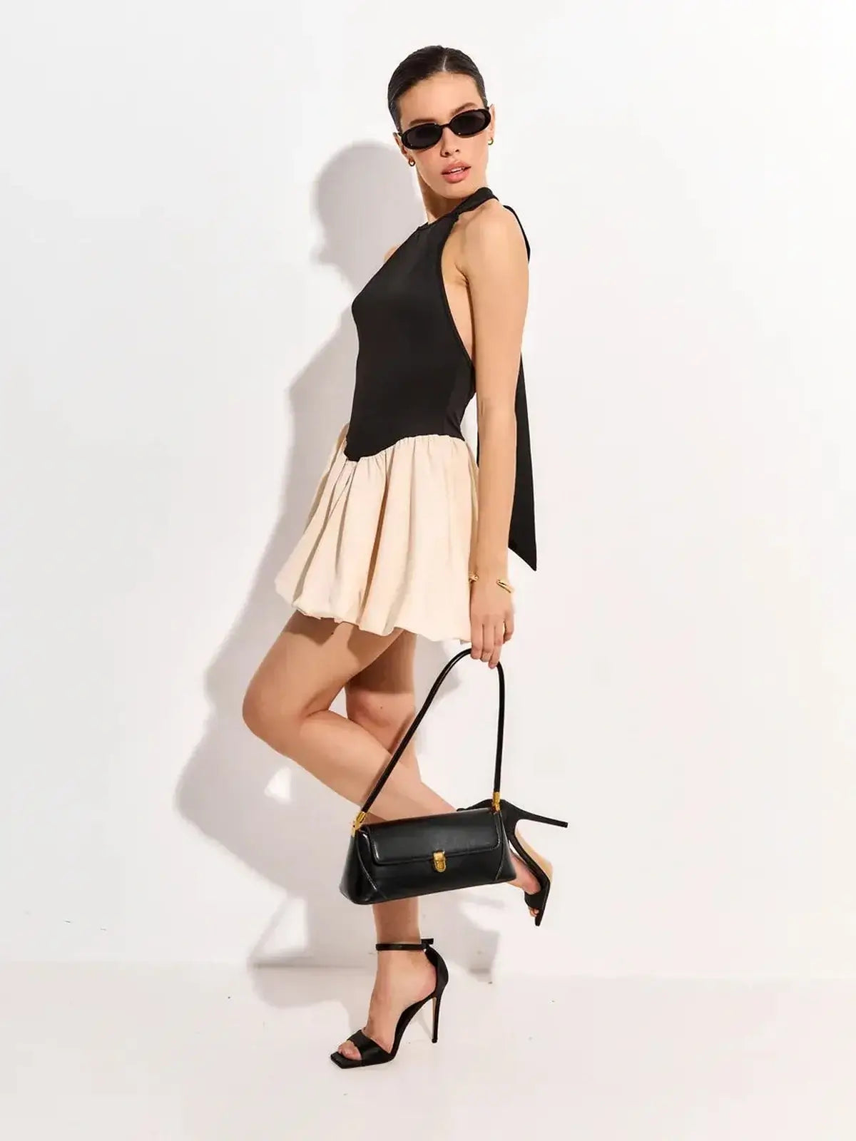 Fashionable black and beige mini dress, perfect for summer parties or wedding guests, paired with stylish accessories.