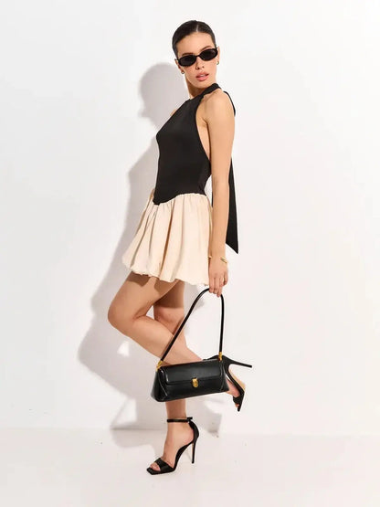 Fashionable black and beige mini dress, perfect for summer parties or wedding guests, paired with stylish accessories.
