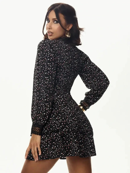 Model wearing Midnight Petals black mini dress with floral accents and long sleeves, showcasing a sleek silhouette.