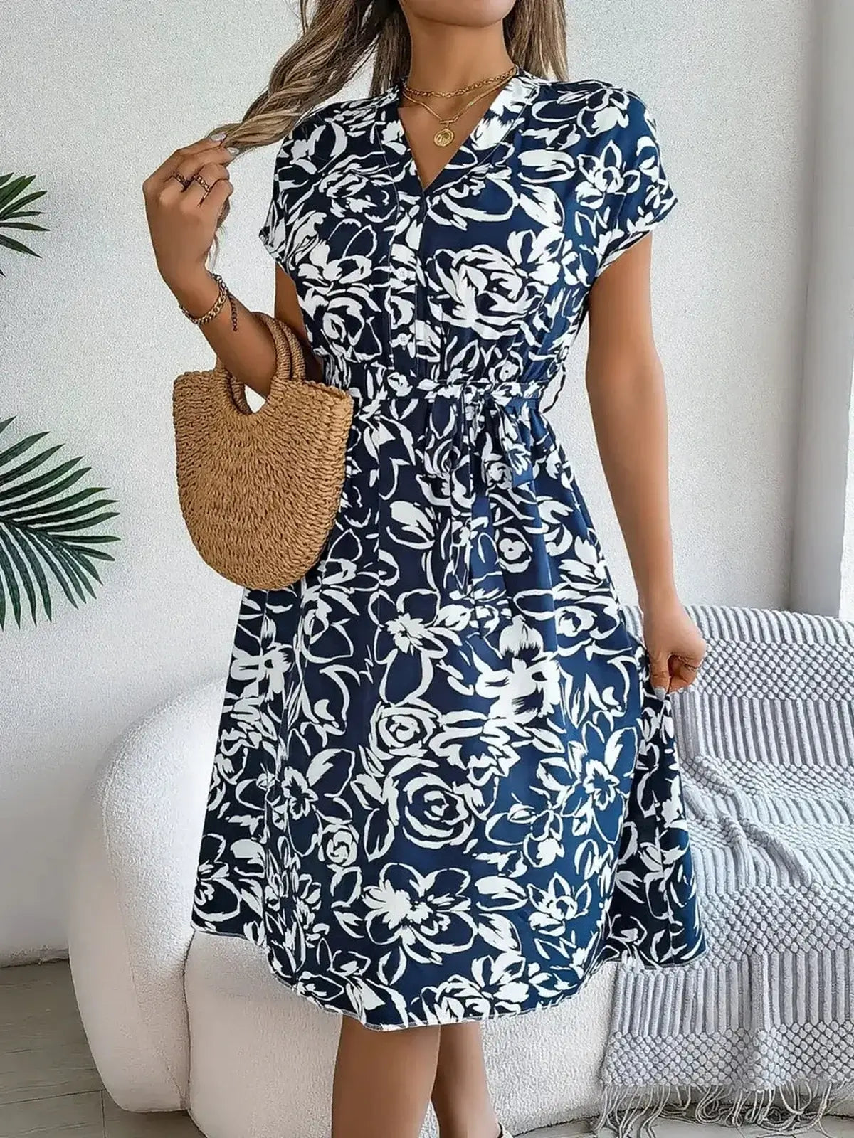 Elegant white-on-navy floral midi dress with V-neckline and cinched waist, perfect for summer occasions.