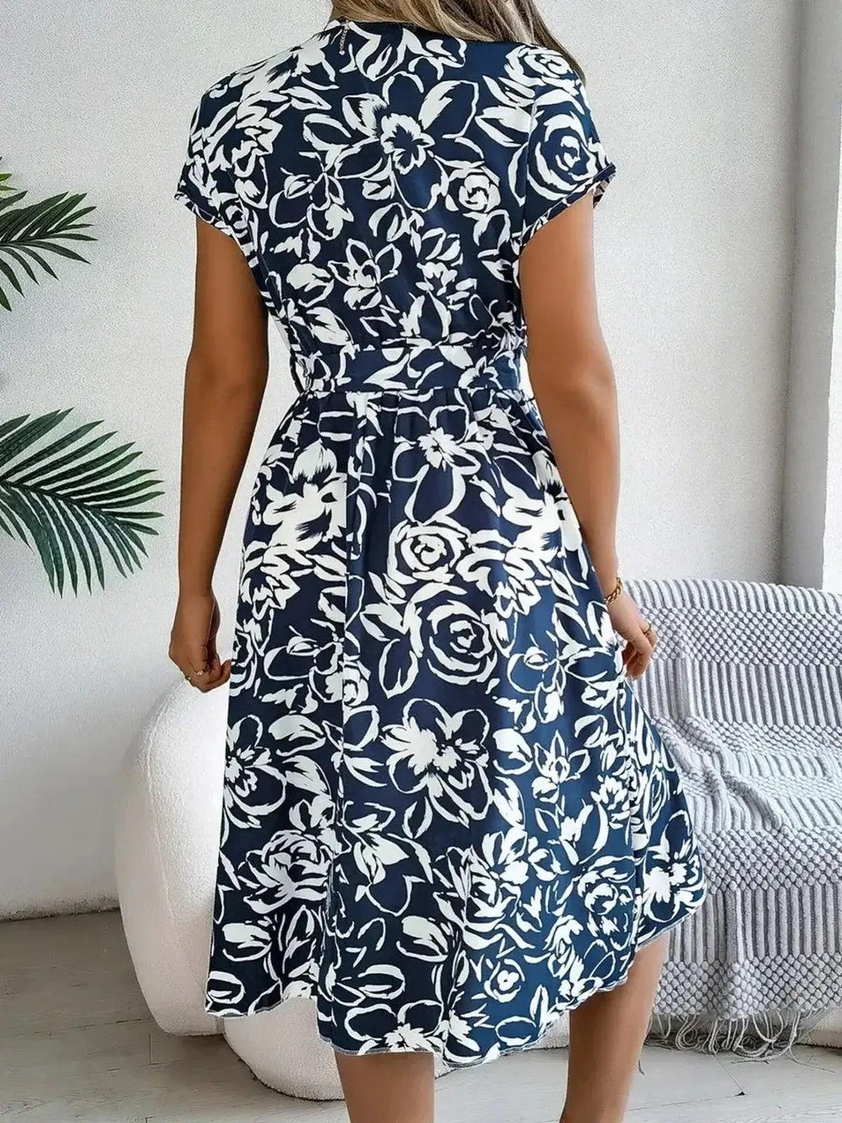 Elegant navy floral midi dress with white petals, featuring a V-neckline and tie belt, perfect for summer occasions.
