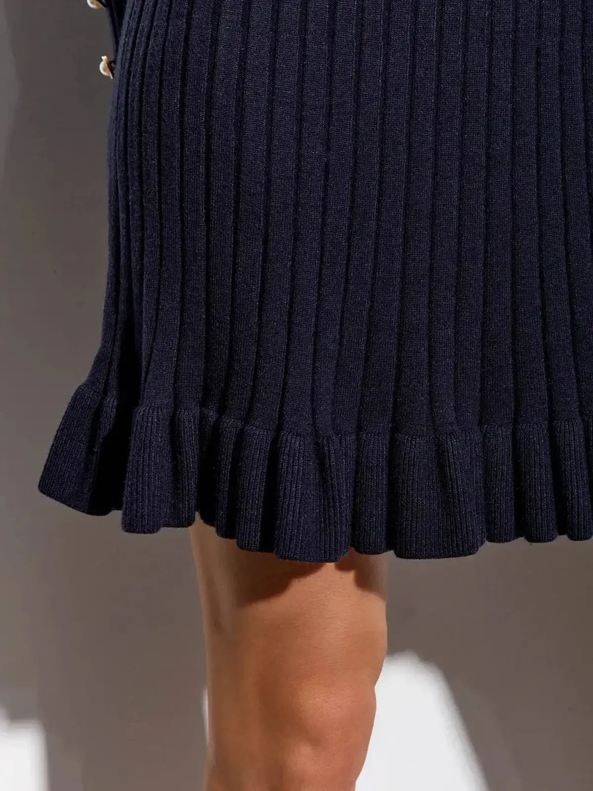 Close-up of a navy mini dress featuring ribbed texture and flared hem for a stylish look.