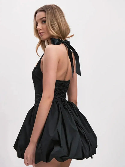 Model wearing a bold black mini dress with voluminous bubble skirt and halter straps, showcasing a modern silhouette.