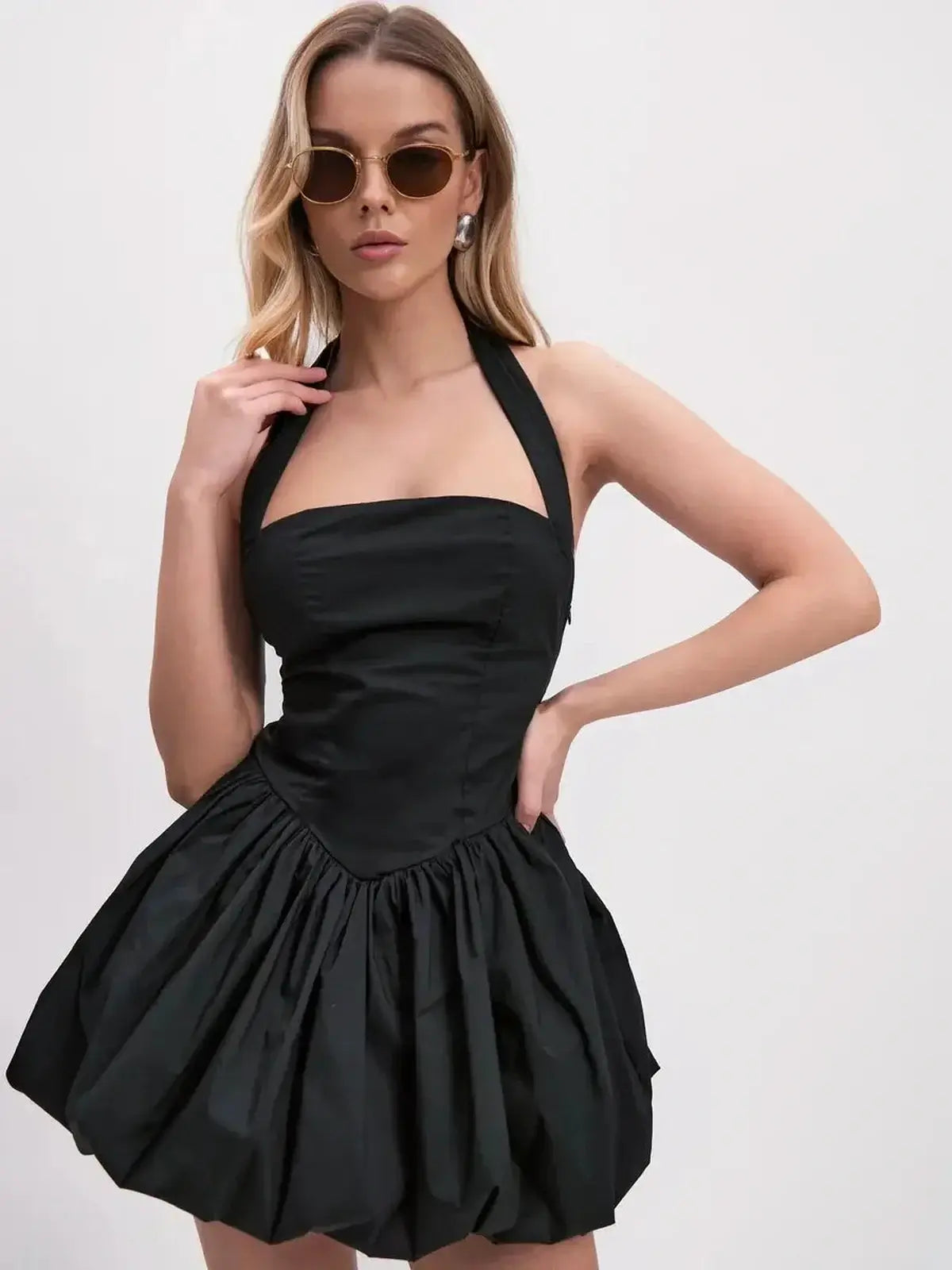 Sculptural black mini dress with wide halter straps and bubble skirt, perfect for cocktail parties.